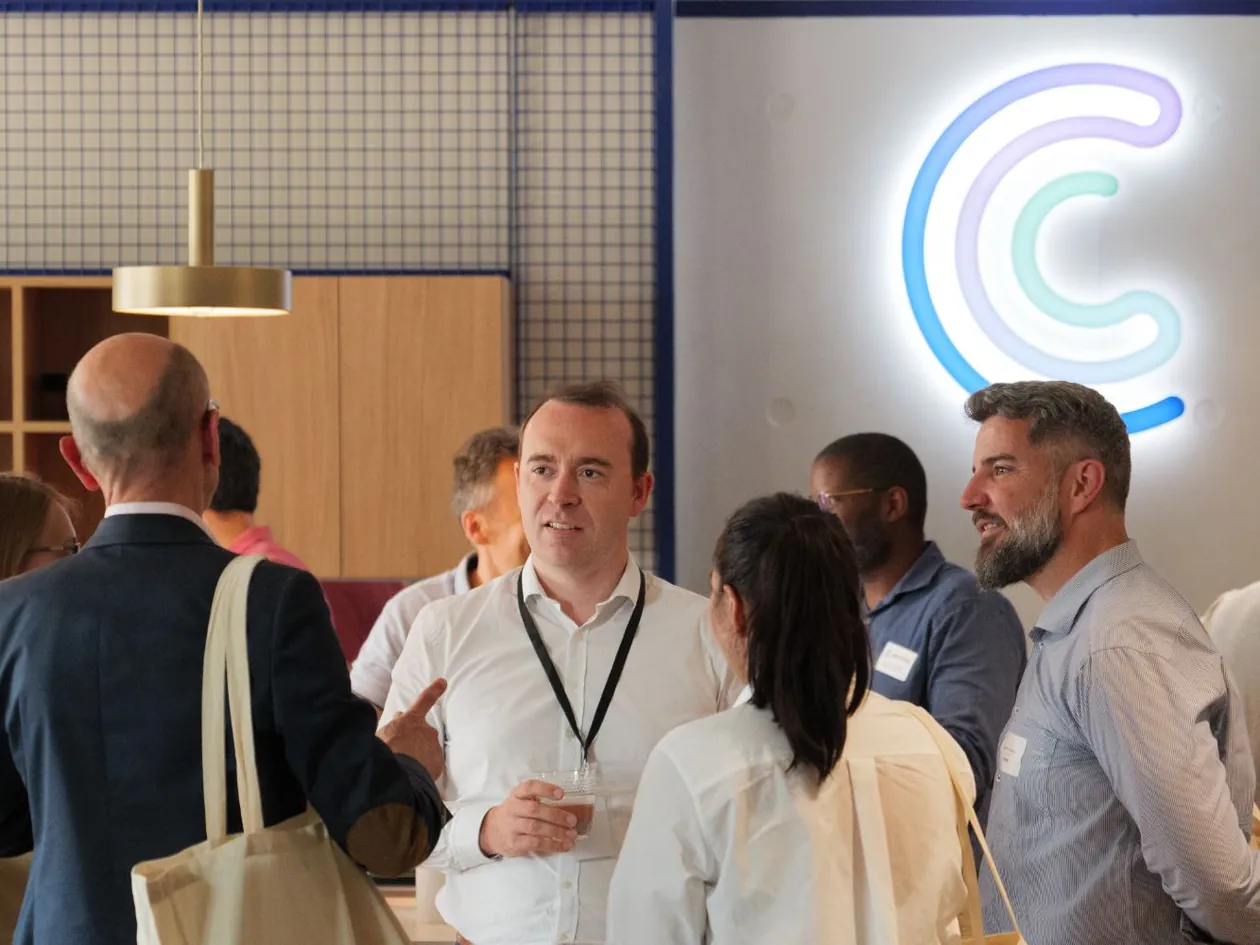 Le CEO de Centreon échange avec des invités lors d’un événement dans les bureaux Centreon, sous le logo lumineux