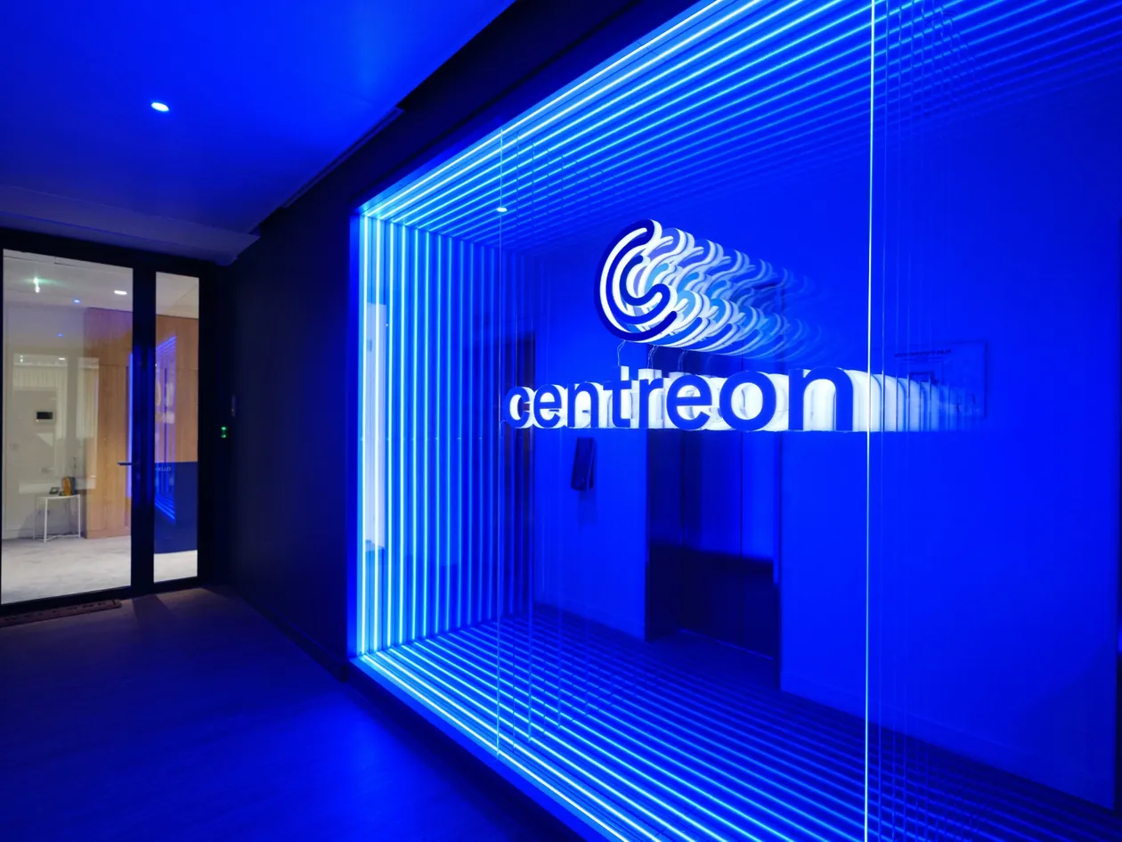Entrée des bureaux Centreon à Paris, logo Centreon éclairé en bleu derrière une paroi vitrée