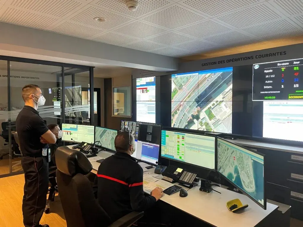 Centre de gestion opérationnel de la Principauté de Monaco : opérateurs devant leurs écrans et mur d'images affichant cartes et compteurs d'interventions en cours